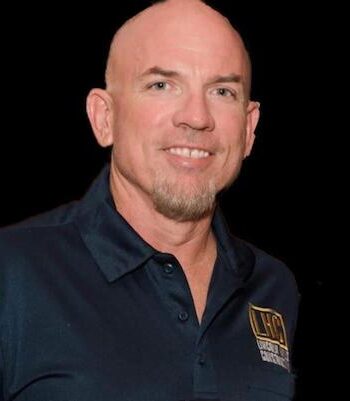 A man with bald head and wearing a blue shirt.