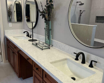 Double vanity with round mirrors and quartz countertop.